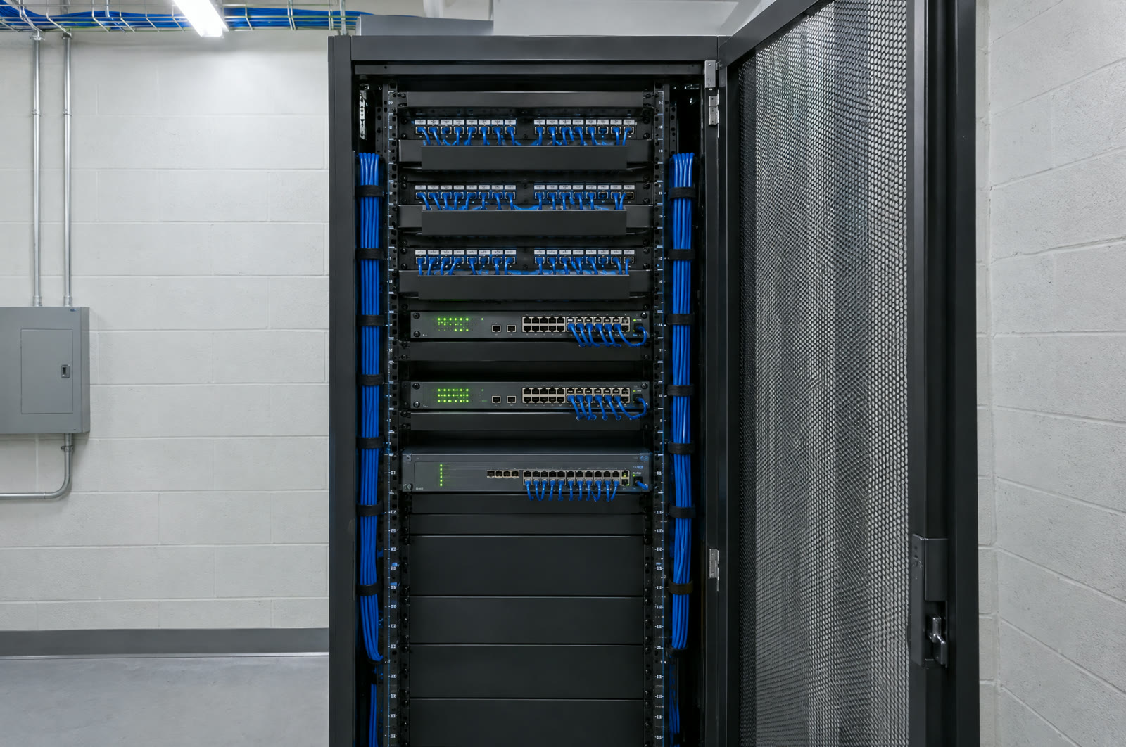 A clean network rack with patch panels, switches and neatly dressed blue patch cords