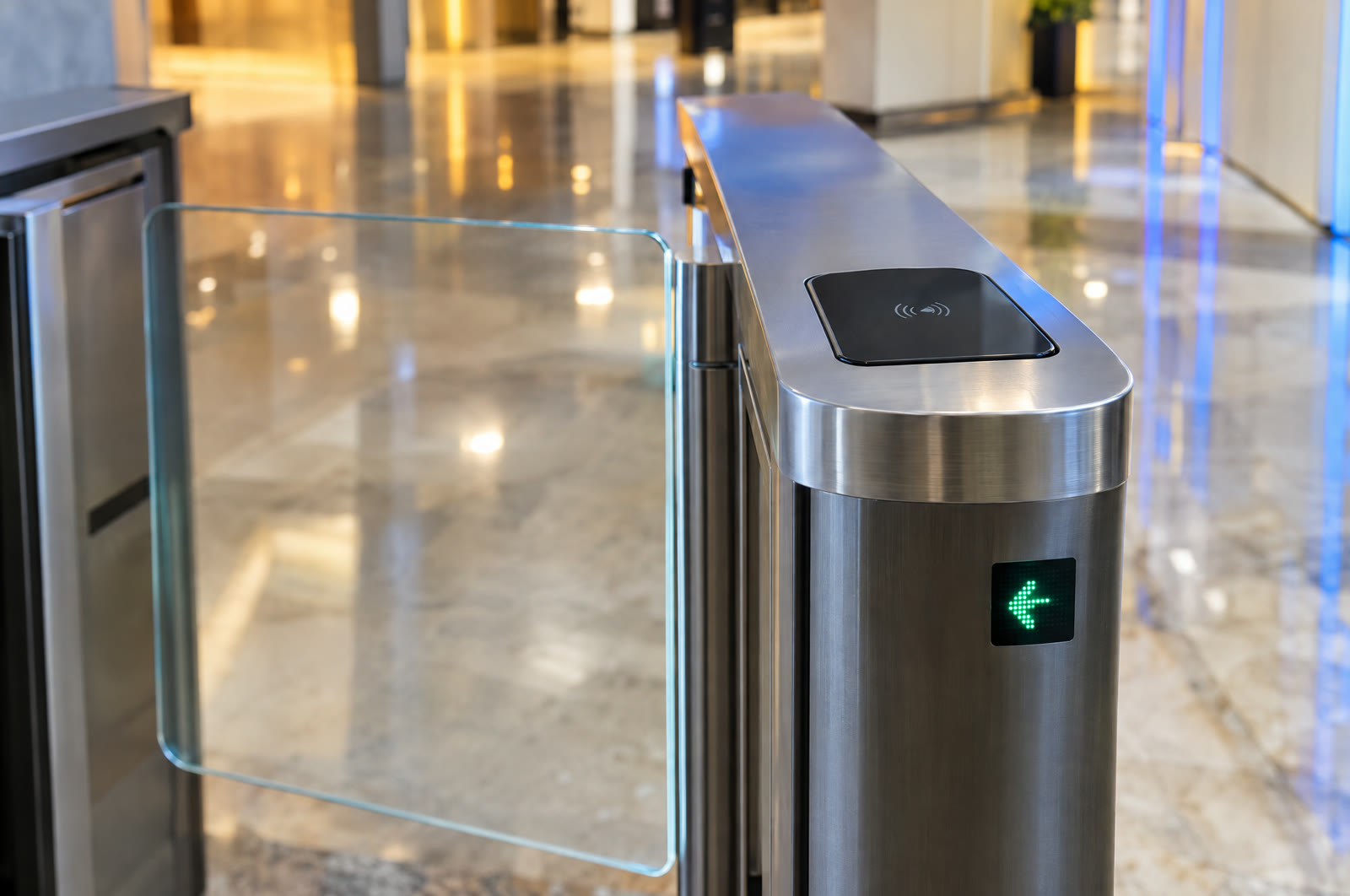 The top of a stainless speed gate with a card reader and a green arrow light